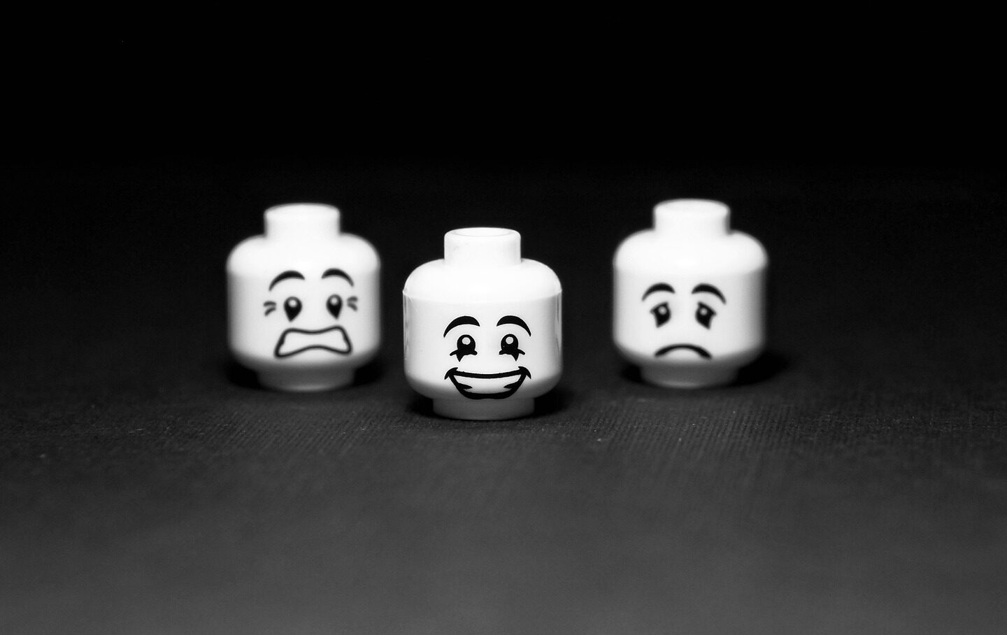 dvě smutné a jedna šťastná LEGO hlavy v černobílé