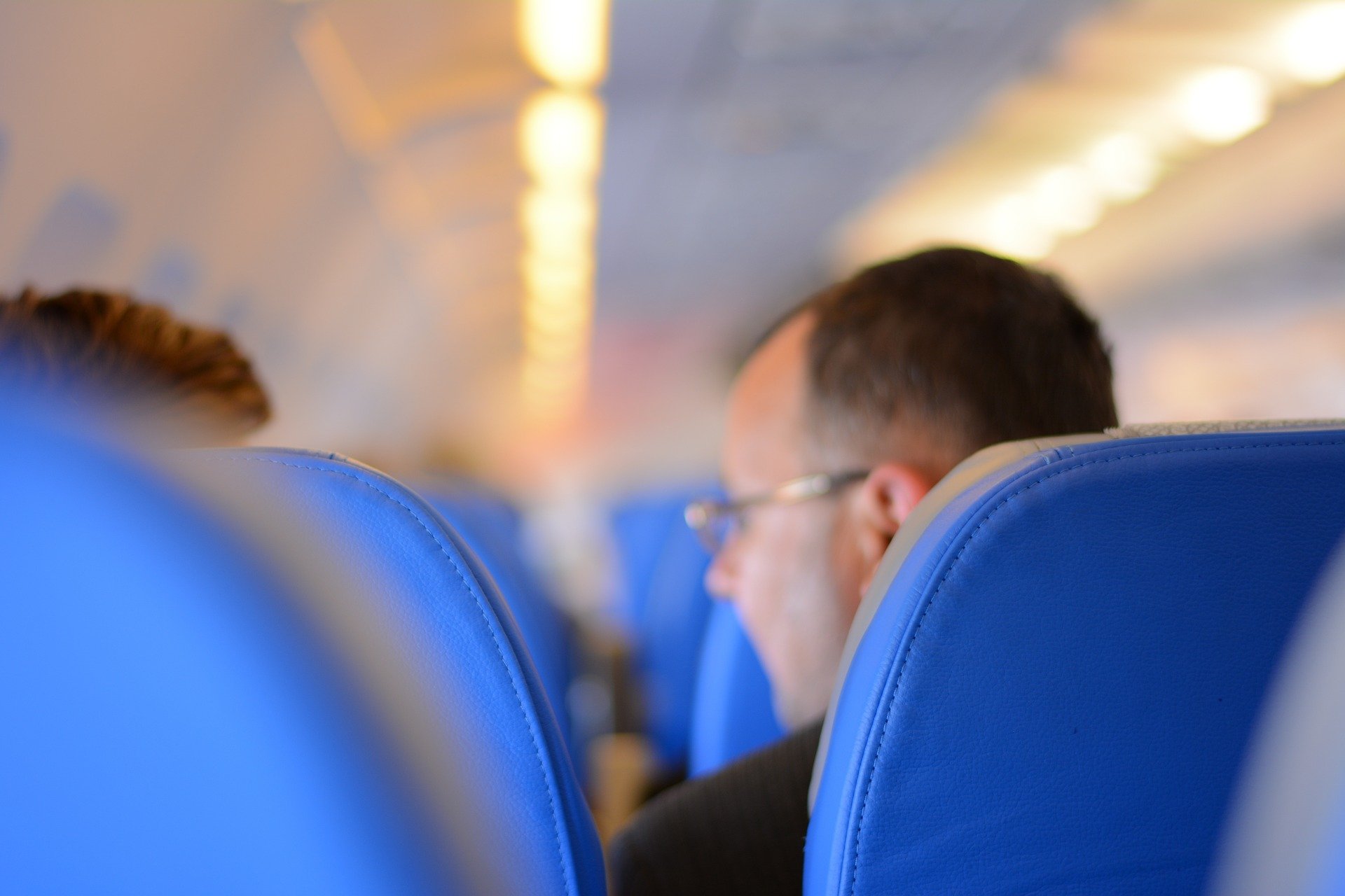lidé nacpaní do ekonomické třídy v letadle, modrá sedadla